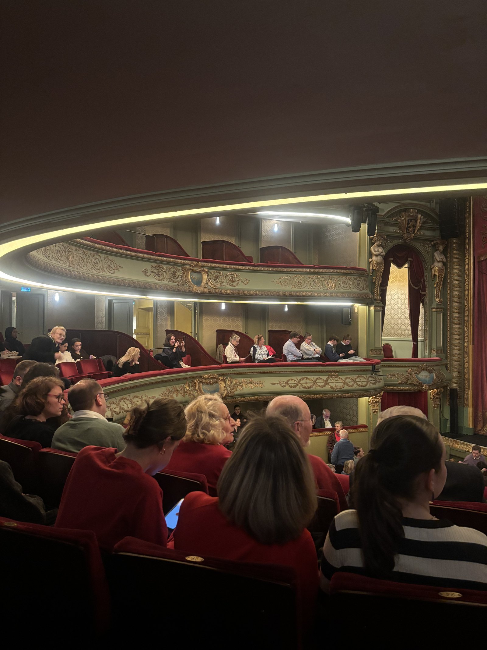 Le public installé dans les sièges rouges du théâtre